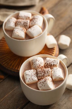 Ahşap arka planda marşmelovlu sıcak kakao bardakları.