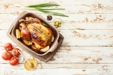 Hafif ahşap arka planda lezzetli tavuk, bal ve sebzeli fırın yemeği.