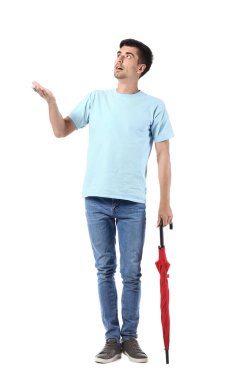 Beyaz arka planda şemsiyesi olan şaşırmış genç bir adam.