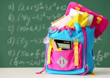 Sınıftaki gözlüklü ve kırtasiyeli okul çantası.