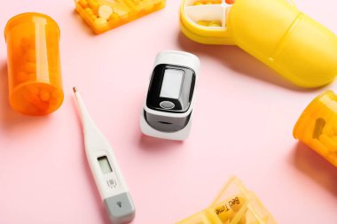 Nabız oksimetresi termometresi ve renkli arka planda haplar.