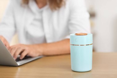 Evde dizüstü bilgisayarı ve modern nemlendiricisi olan genç bir adam var.