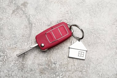 Grunge arka planında ev şekli anahtarlığı olan kırmızı araba anahtarı
