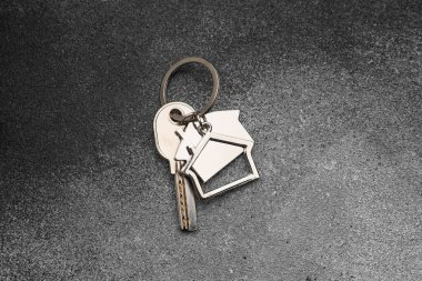 Koyu arkaplanda ev şekli anahtarlığı olan anahtar