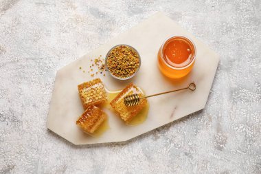 Işık arka planında bal kavanozu, tarak ve arı poleni