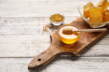 Bal kaseleri ve beyaz ahşap arka planda taraklar