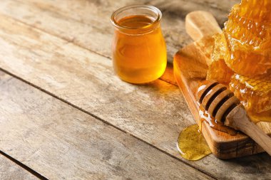 Bir kavanoz bal, taraklar ve dipper ahşap arka planda, yakın plan