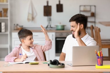 Evde babasıyla küçük bir çocuk beşlik çakıyor.