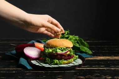 Masada lezzetli bir vejetaryen burger hazırlayan kadın.