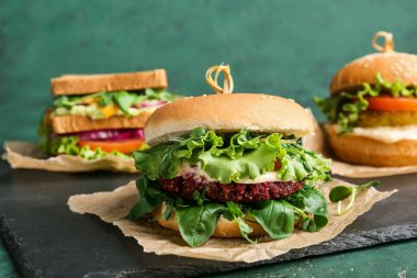 Yeşil arka planda lezzetli vejetaryen burgerleri olan pano.
