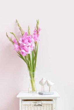 Renk duvarına karşı masasında güzel gladiolus çiçekleri olan vazo.