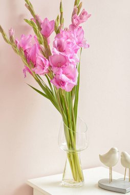 Renk duvarına karşı masasında güzel gladiolus çiçekleri olan vazo.