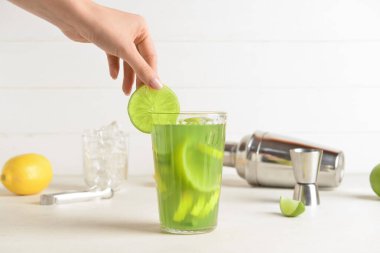 Hafif arka planda bir bardak lezzetli limonata ile bir kadın eli.