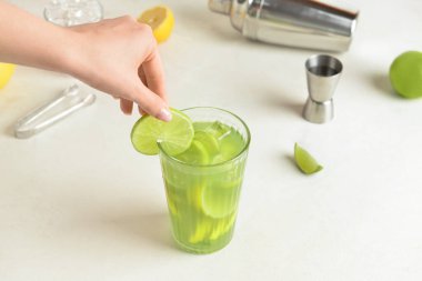 Hafif arka planda bir bardak lezzetli limonata ile bir kadın eli.