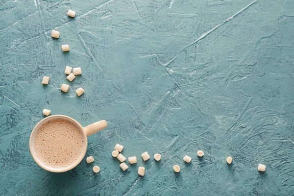 Renkli arkaplanda bir fincan sıcak kakao ve marşmelov karışımı.