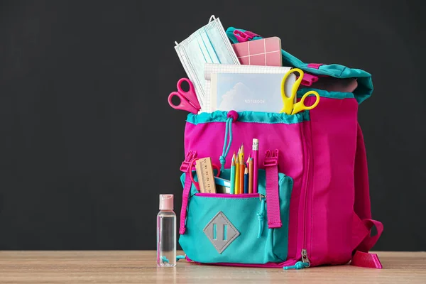 Schulrucksack Mit Schreibwaren Medizinischer Maske Flasche Desinfektionsmittel Auf Dunklem Hintergrund — Stockfoto