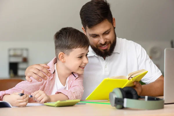 Babasıyla evde ders alan küçük bir çocuk.