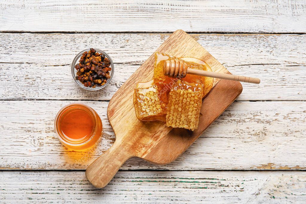 Jar of honey, combs and beebread on white wooden background