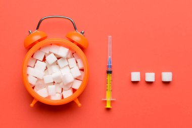 Renk arkaplanında şeker ve şırıngayla alarm saati