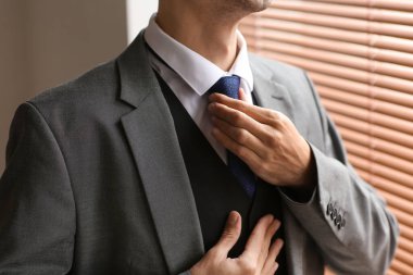 Pencerenin yanındaki şık takım elbiseli genç adam.