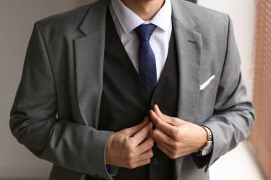 Evde şık giyinmiş genç bir adam var.