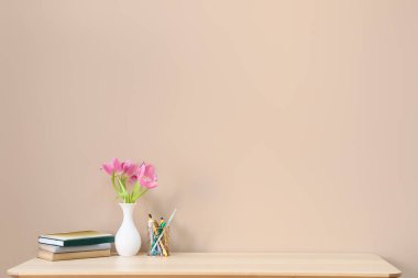 Renk duvarının yanında güzel çiçekleri, defterleri ve kalem tutacağı olan şık bir iş yeri.