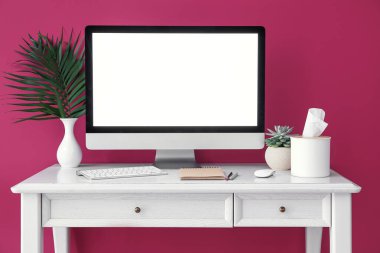 Renk duvarına yakın modern bilgisayar ve klavyesi olan şık bir iş yeri