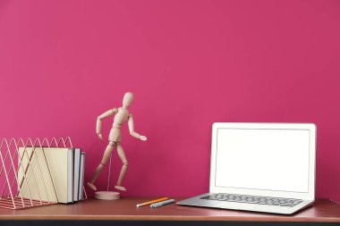 Renk duvarının yanında dizüstü bilgisayarı ve dekoru olan modern işyeri
