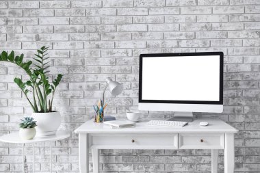 Gri tuğla duvarın yanında modern bilgisayarlı şık bir iş yeri.