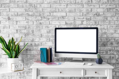 Gri tuğla duvarın yanında modern bilgisayarlı şık bir iş yeri.