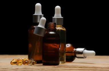 Kozmetik şişeleri ve haplar karanlık arka plana karşı masada.