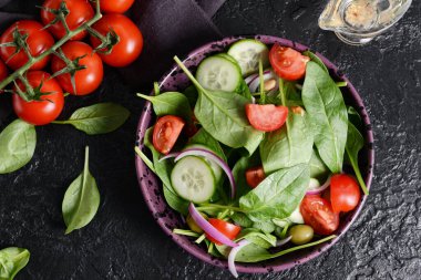 Koyu arkaplanda sağlıklı taze salata tabağı.