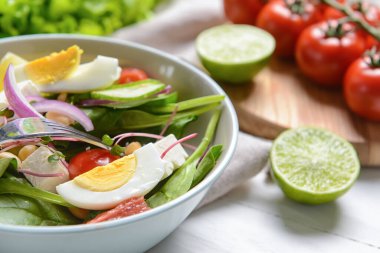 Sağlıklı salata ve hafif ahşap arka planda yumurtalar.