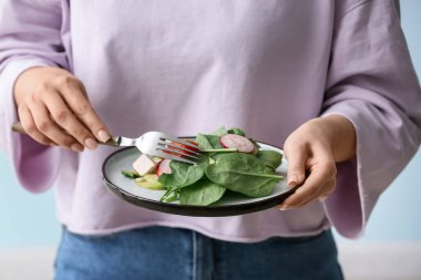 Hafif arka planda sağlıklı salata yiyen kadın, yakın plan.