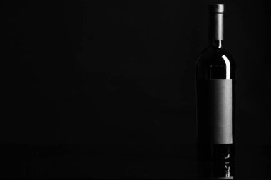 Siyah arka planda bir şişe şarap.