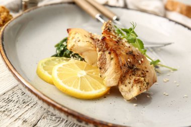 Lezzetli kızarmış morina filetosu, pesto sosu ve limonlu tabak, ahşap kaplama, yakın plan.