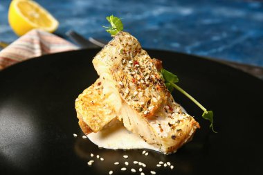 Lezzetli kızarmış morina filetosu, yeşillik ve soslu tabak.