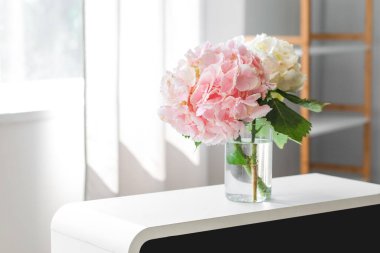 Pencerenin yanındaki rafta ortanca çiçekli vazo