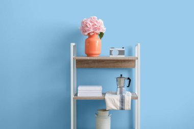 Ortanca çiçekli vazo ve renk duvarının yanındaki rafta dekor.