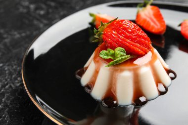 Koyu arkaplanda lezzetli çilekli panna cotta tabağı, yakın plan.