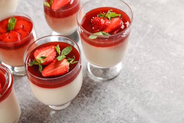 Lezzetli çilekli panna cotta ve nane arkaplanlı bardaklar.