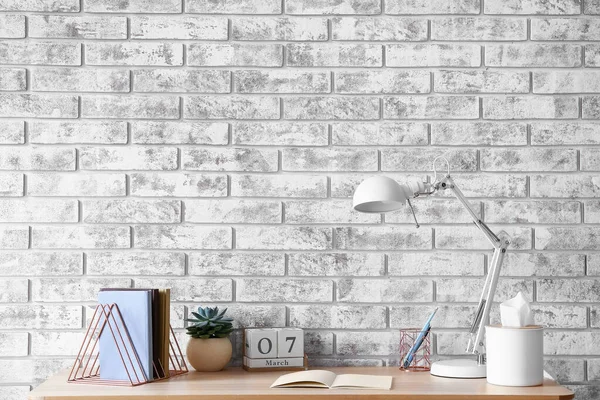 レンガの壁の近くにノートとモダンなランプのスタイリッシュな職場 — ストック写真