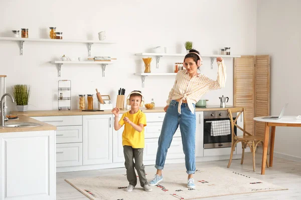 Genç kadın ve küçük oğlu mutfakta dans edip müzik dinliyorlar.