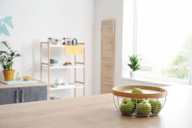 Mutfaktaki ahşap masada taze elmalı sepet.