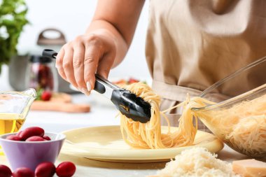 Mutfak masasında Puttanesca makarnası hazırlayan kadın, yakın plan.