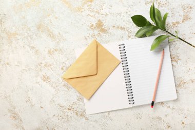 Hafif arkaplanda defter, kalem ve zarf