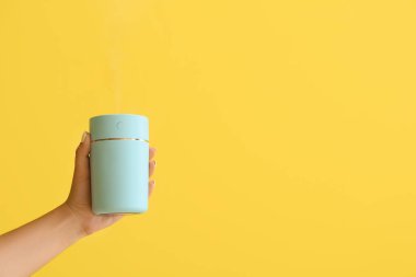 Renkli arka planda modern hava nemlendiricisi olan kadın eli