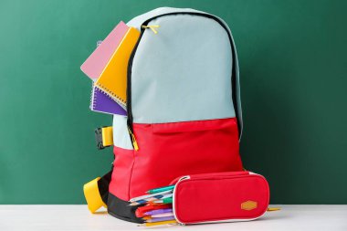 Süslü okul çantası, kalem kutusu ve karatahtaya karşı kırtasiye.