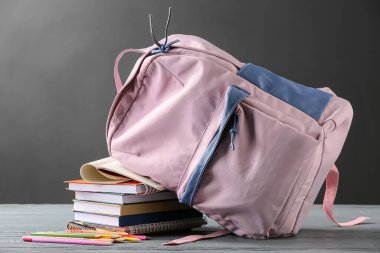 Okul çantasında kırtasiye malzemeleri ve kitaplar var.