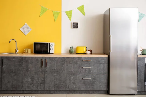 Interior of kitchen with modern microwave oven and refrigerator